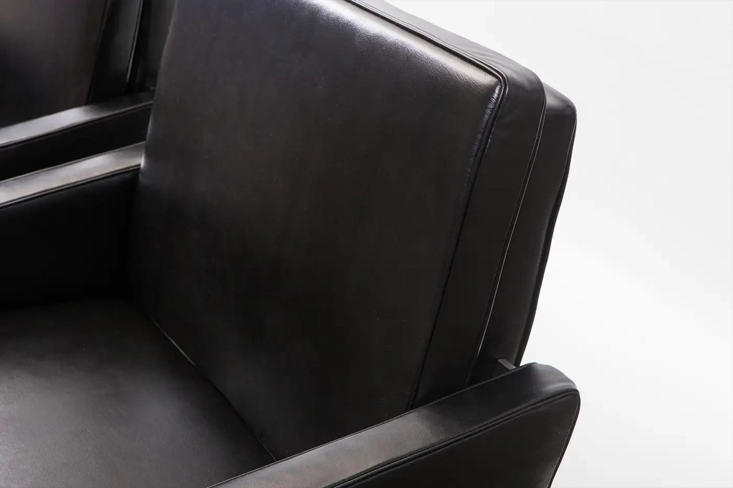 Close-up of a black leather seat with a white background